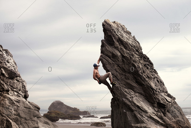 Man scaling a rock at the coast