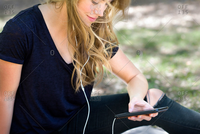 A young woman listens to music on her smartphone