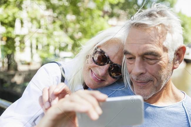 Senior couple taking a selfie at town canal