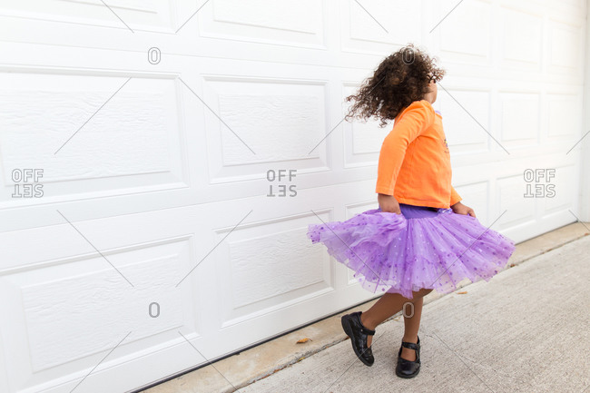 Girl in tulle skirt twirling by garage door