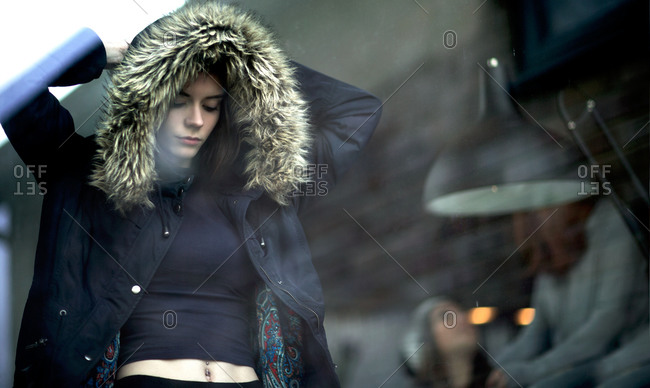 Teenaged girl in hooded jacket reveals belly button piercing