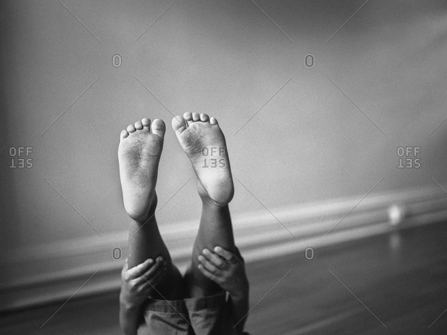 Feet of a little boy holding his legs up in the air