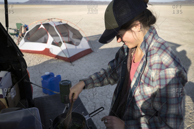 Woman cooking on a camp stove in a cracked sand desert