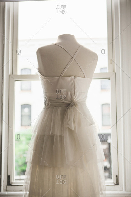 Back view of wedding gown on a dress form in front of window