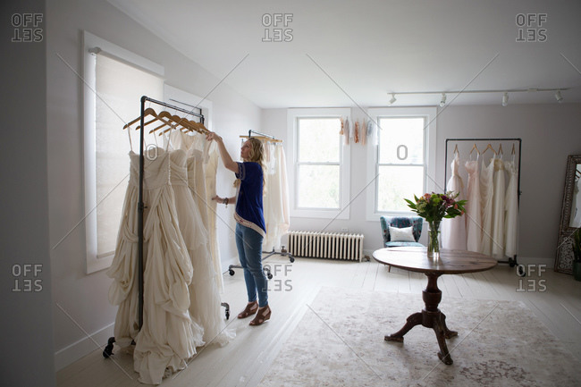Wedding dress designer looks at her rack of sample designs