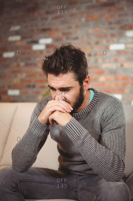 Stressed man with hands in front of mouth at home