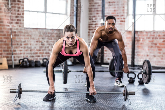 Fit couple squatting down to lift weights