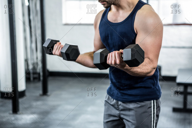 Heavy dumbbells being lifted by a fit man in a gym