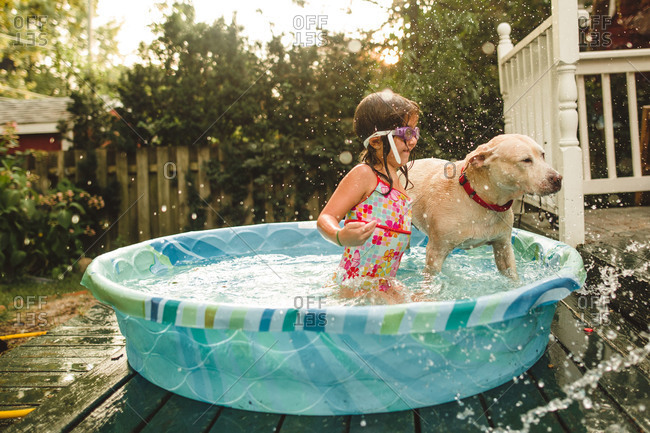 Girl playing with her dog in a kiddie pool