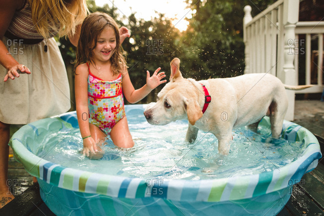 Girl in a kiddie pool with her dog
