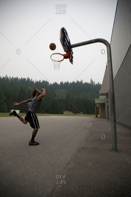 Man tossing basketball in rural parking lot