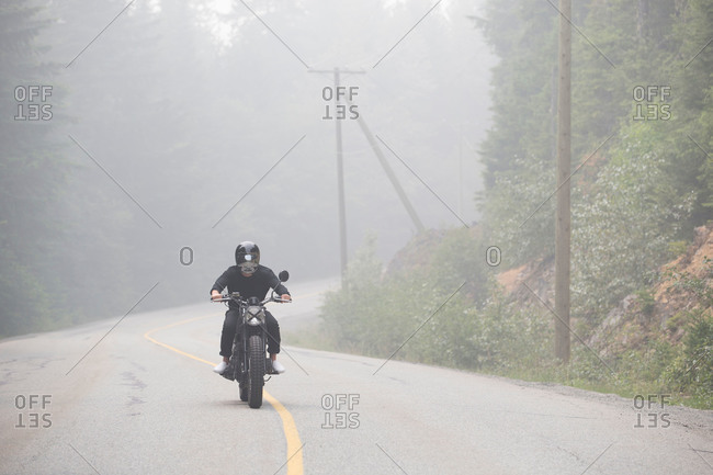 Man on motorcycle on misty rural highway