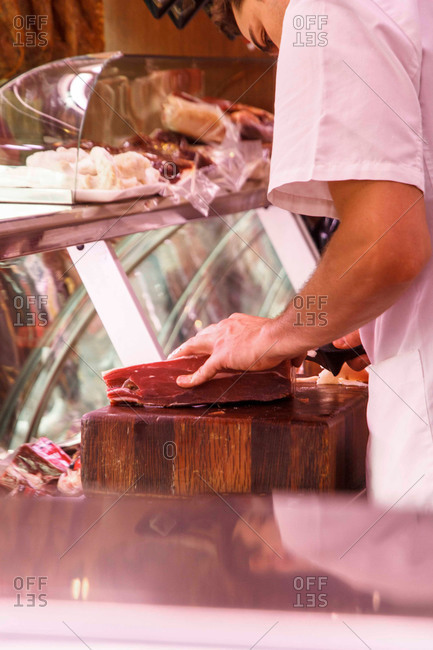 Butcher slicing meat at a deli counter