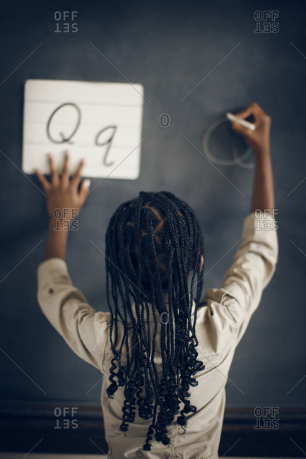 Girl practicing writing cursive letters on chalkboard
