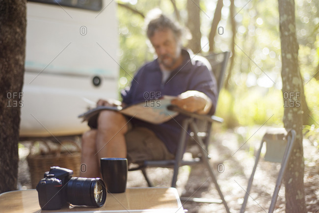 Older man reading newspaper at campsite