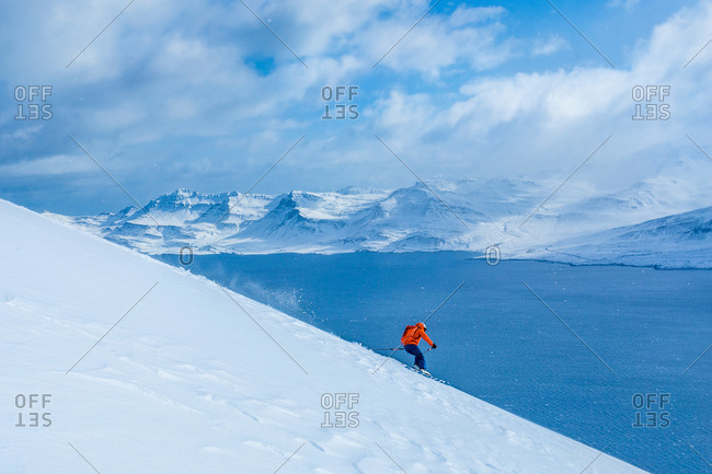 A skier riding down a steep hill in the Icelandic fjords