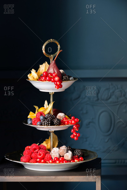 A three-tiered fruit tray in a blue room