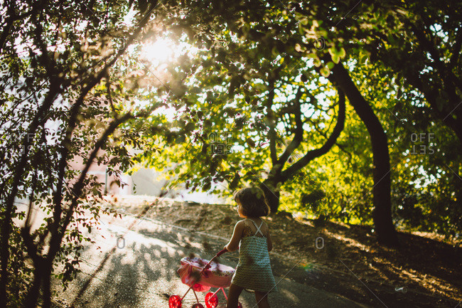 Girl pushing her doll stroller in a park