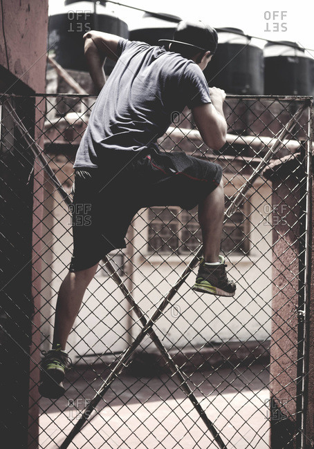 Athletic young man climbing over a fence