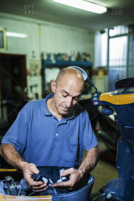 Mechanic working in his motor scooter workshop