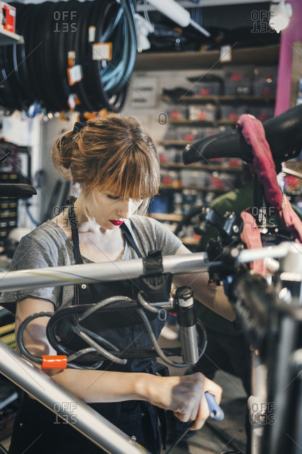 Mid adult mechanic repairing bicycle in a workshop