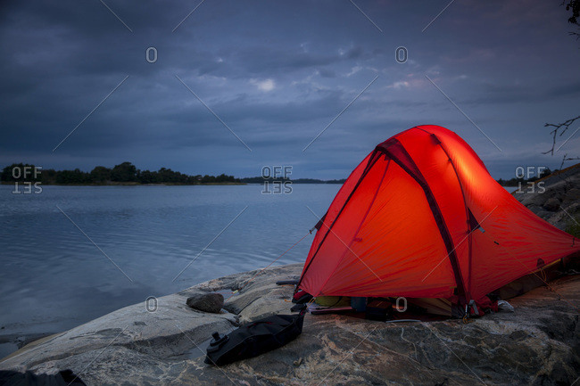 Tent on rock at  a lakeshore during dusk