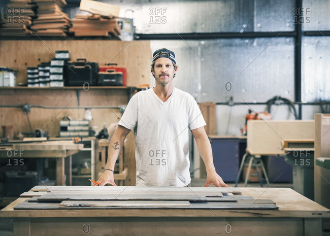 Portrait of confident carpenter standing at workbench in a workshop