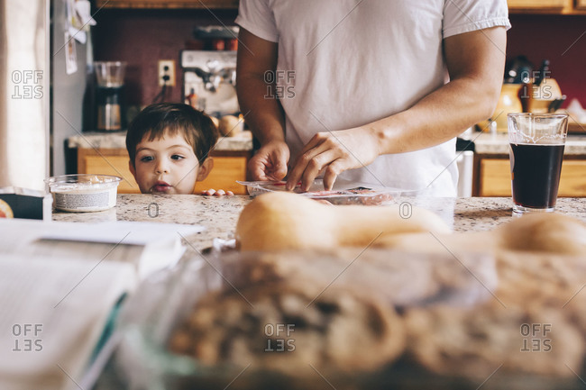 Child peers over counter while man preps Thanksgiving food