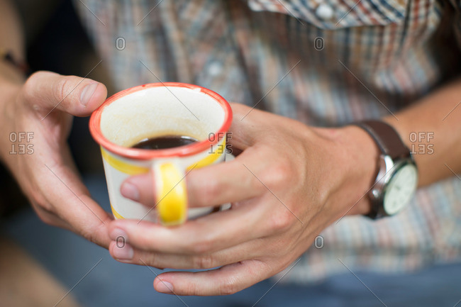 One person at a picnic table outdoors, holding a china mug