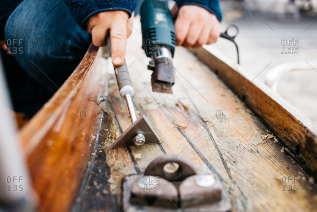 Man using tools to strip varnish from boat