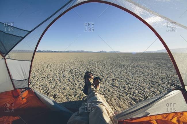 Man in his tent taking in the view of desert and playa in Black Rock Desert, Nevada