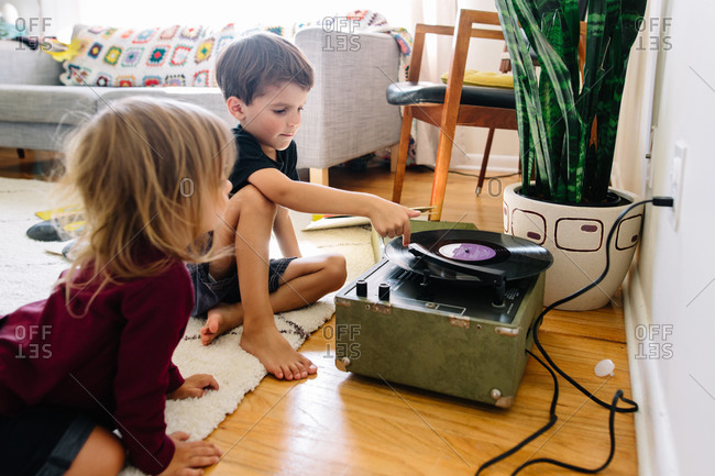 Siblings listen to records on the floor
