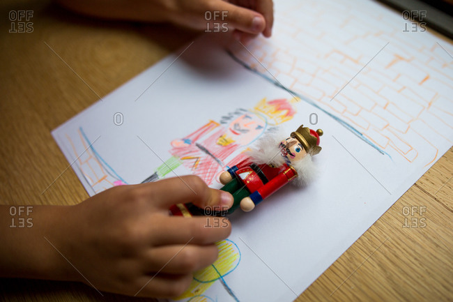 Child holding a small nutcracker figure up to drawing of the nutcracker