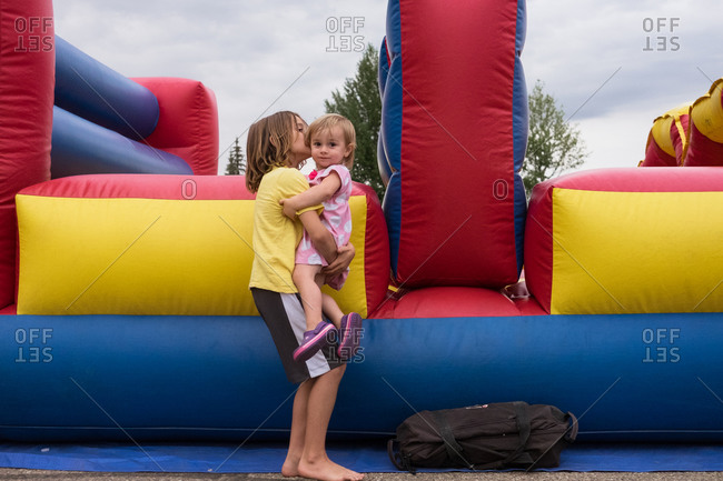 Boy holding sister by inflatable bounce house