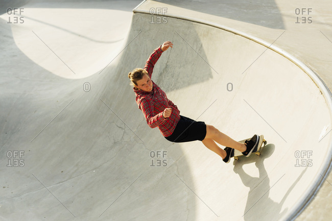 Young woman riding a skateboard on a bowl at an urban skate park