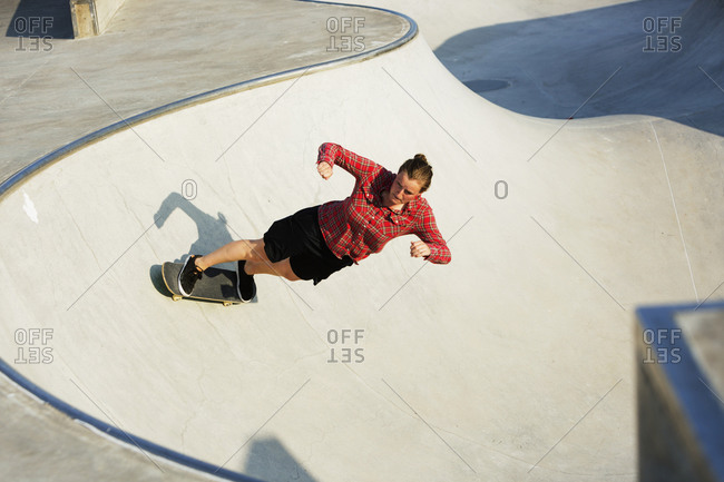 Young woman riding a skateboard in a bowl at an urban skate park