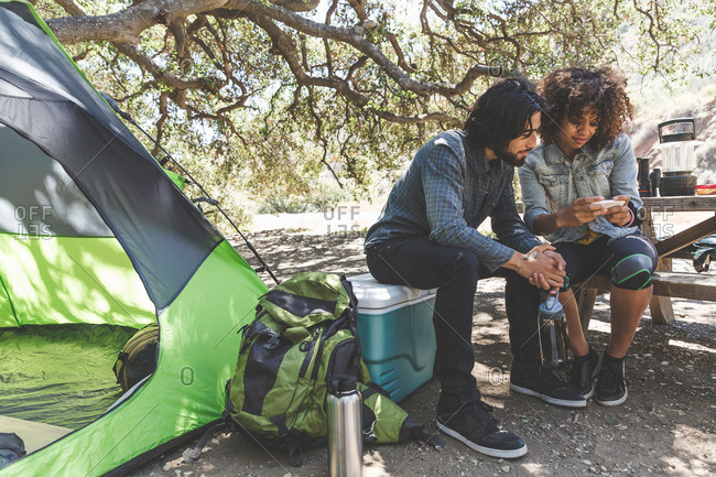 Couple viewing pictures on cell phone together while camping