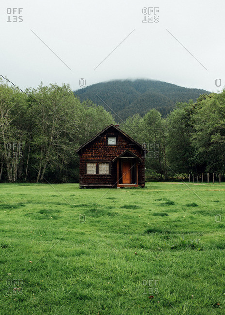 Rustic wood cabin in a field below mountain