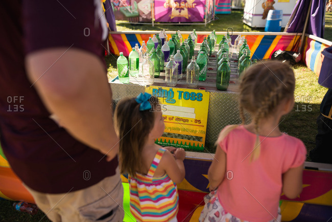 Girls standing at a ring toss game at a fair