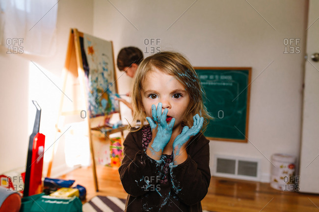 Little girl putting a paint-covered finger in her mouth