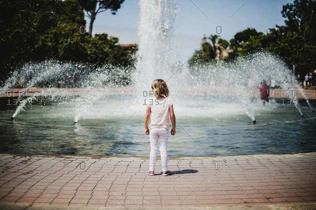 Back view of young girl standing at fountain