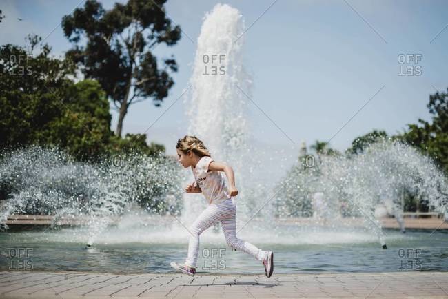 Young girl running around fountain