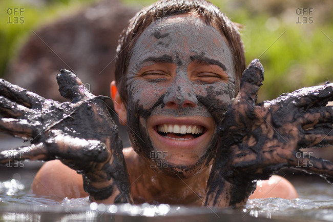 Close up portrait of an adult woman in the water with mud on her hands and face