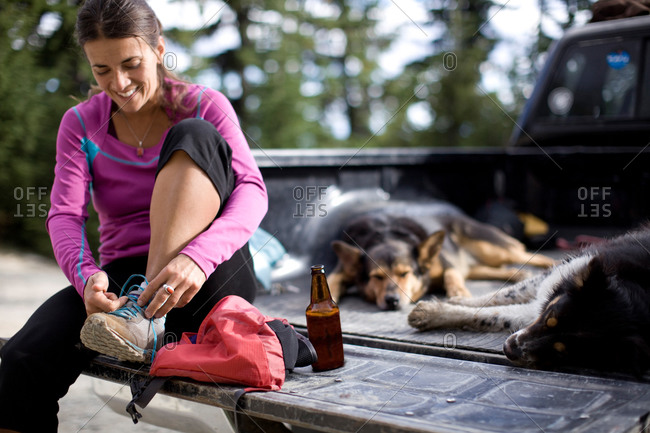 Adult woman enjoying a beer on her tailgate with her dogs after a trail run