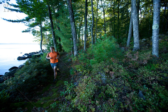 An adult man running on a path along a lake