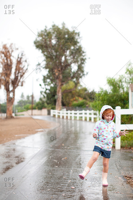 Girl in raincoat playing in the rain