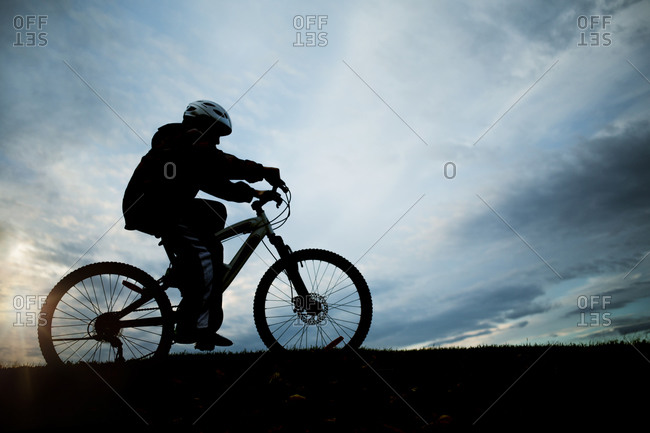 Little boy riding his bike at sunset