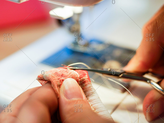 Close-up of woman cutting thread at sewing machine