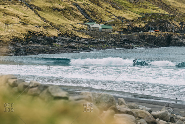 Surfer on wave off Faroe Islands, Denmark