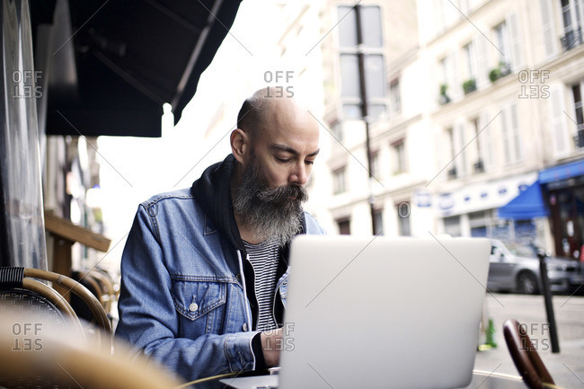 Man with laptop sitting outside cafe